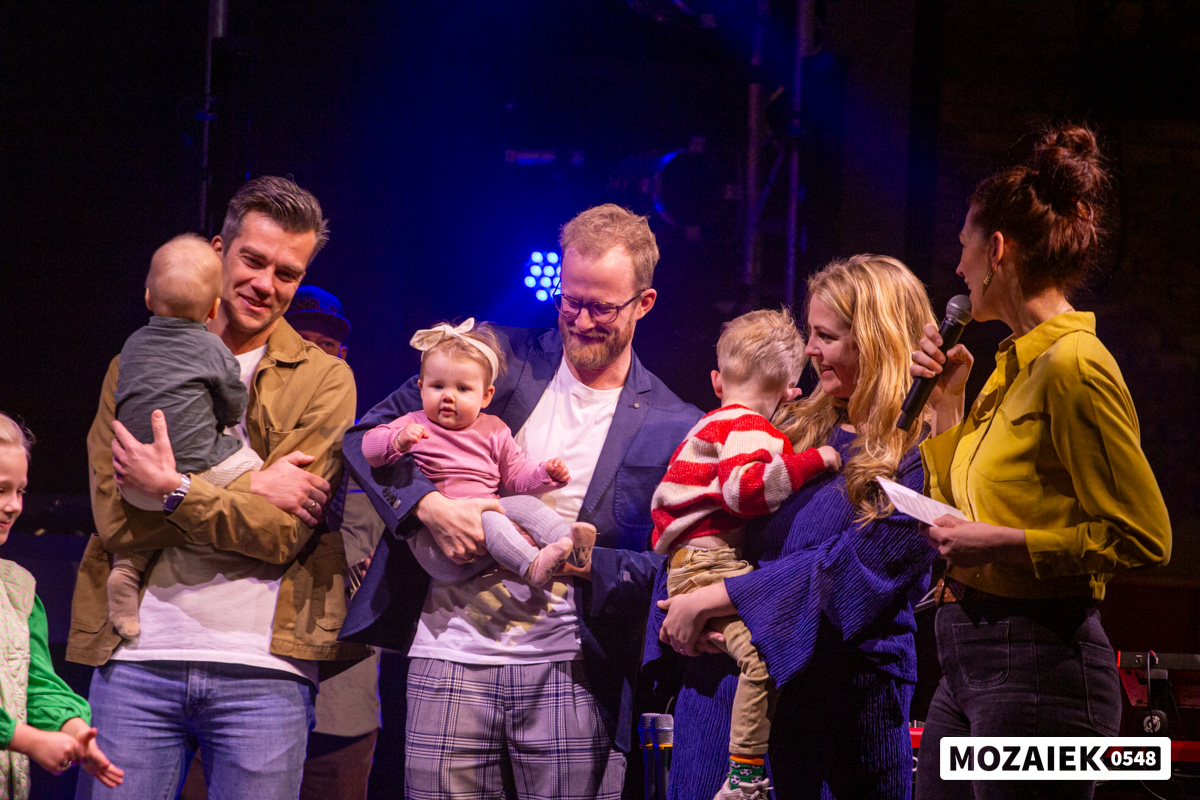 Vaders en moeders met hun baby's en kinderen op het podium tijdens een opdraagdienst van Mozaiek0548