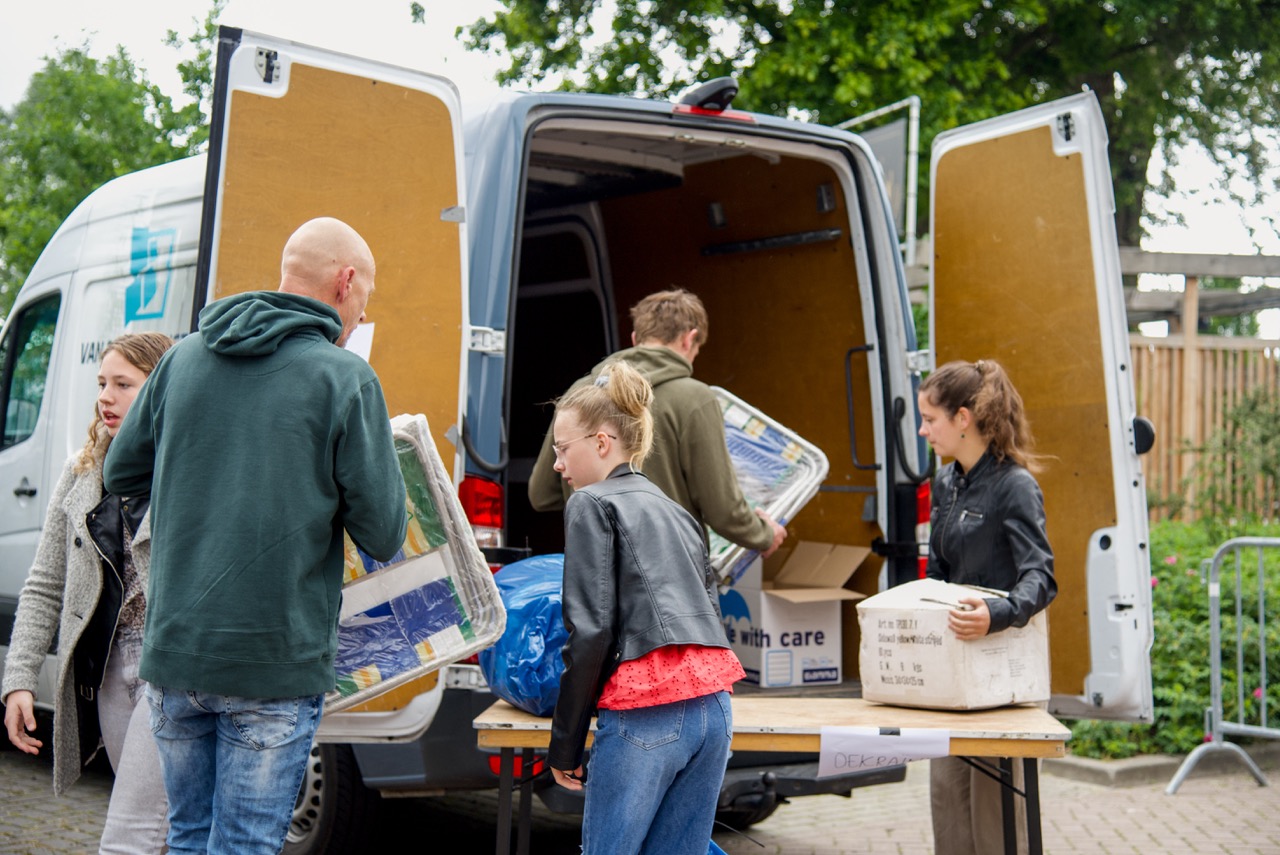 Bezoekers laden dozen en spullen in een bestelbus tijdens een inzamelactie