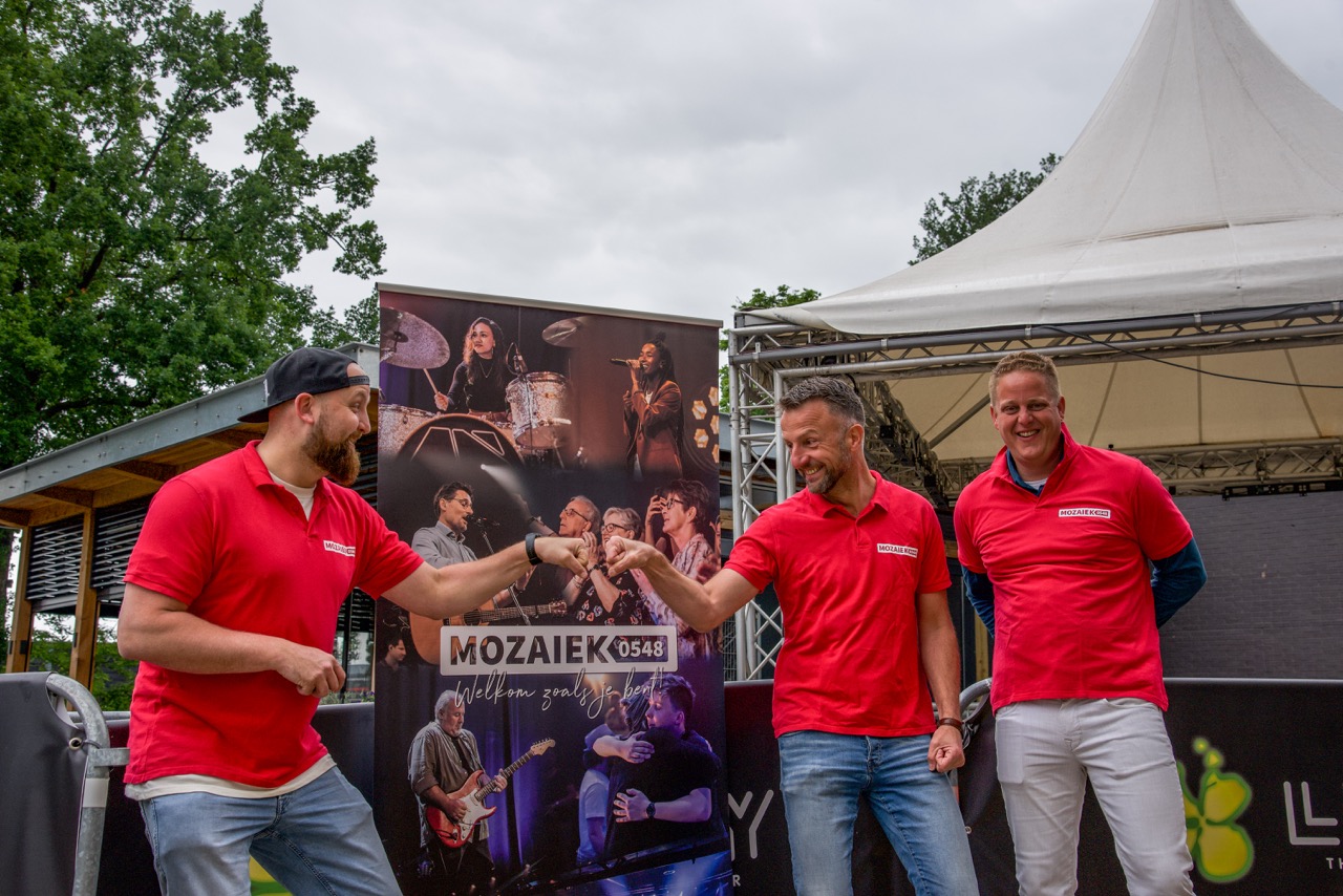 Twee teamleden in rode shirts geven elkaar een boks bij de tent