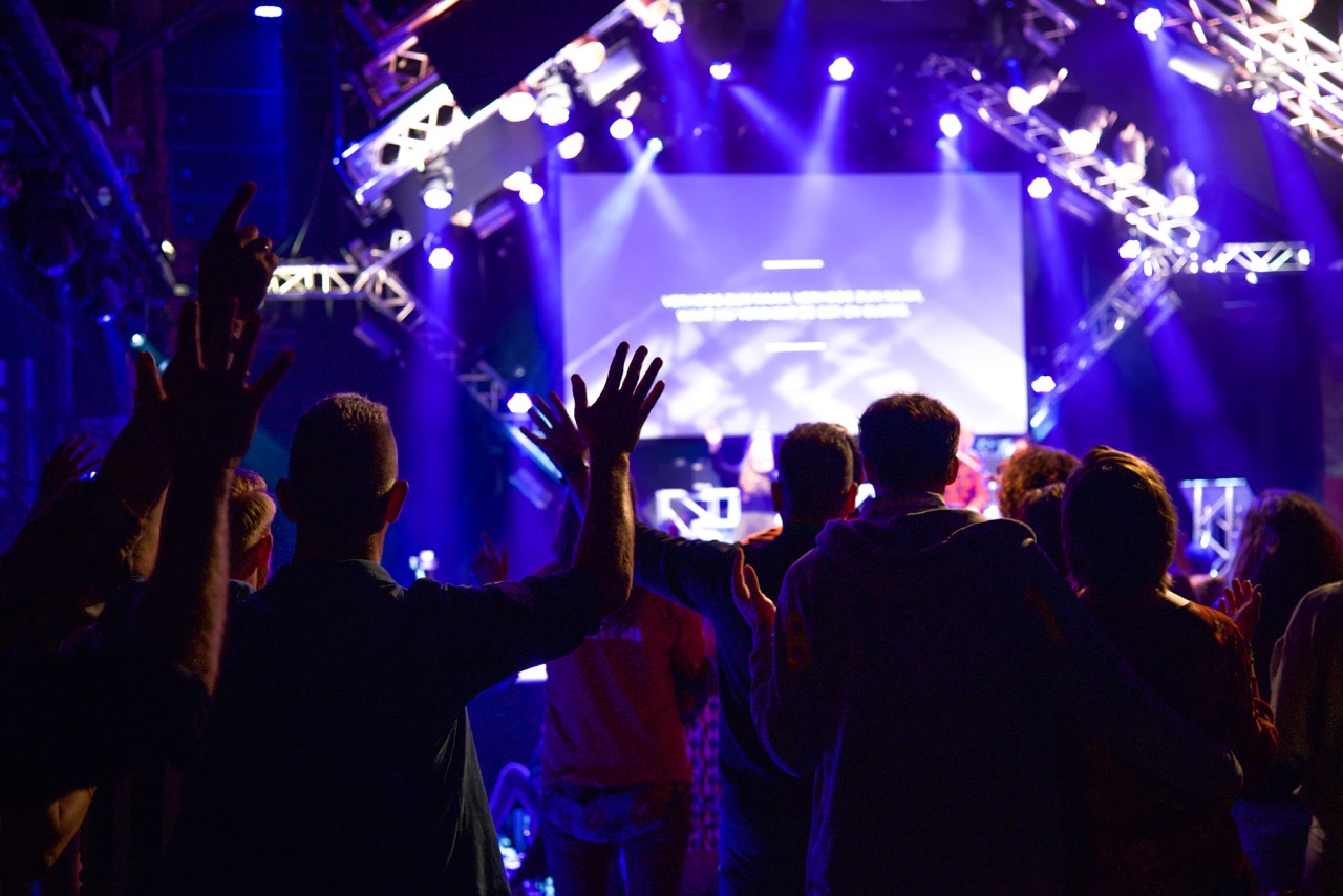 Bezoekers met opgeheven handen in de zaal tijdens de worship