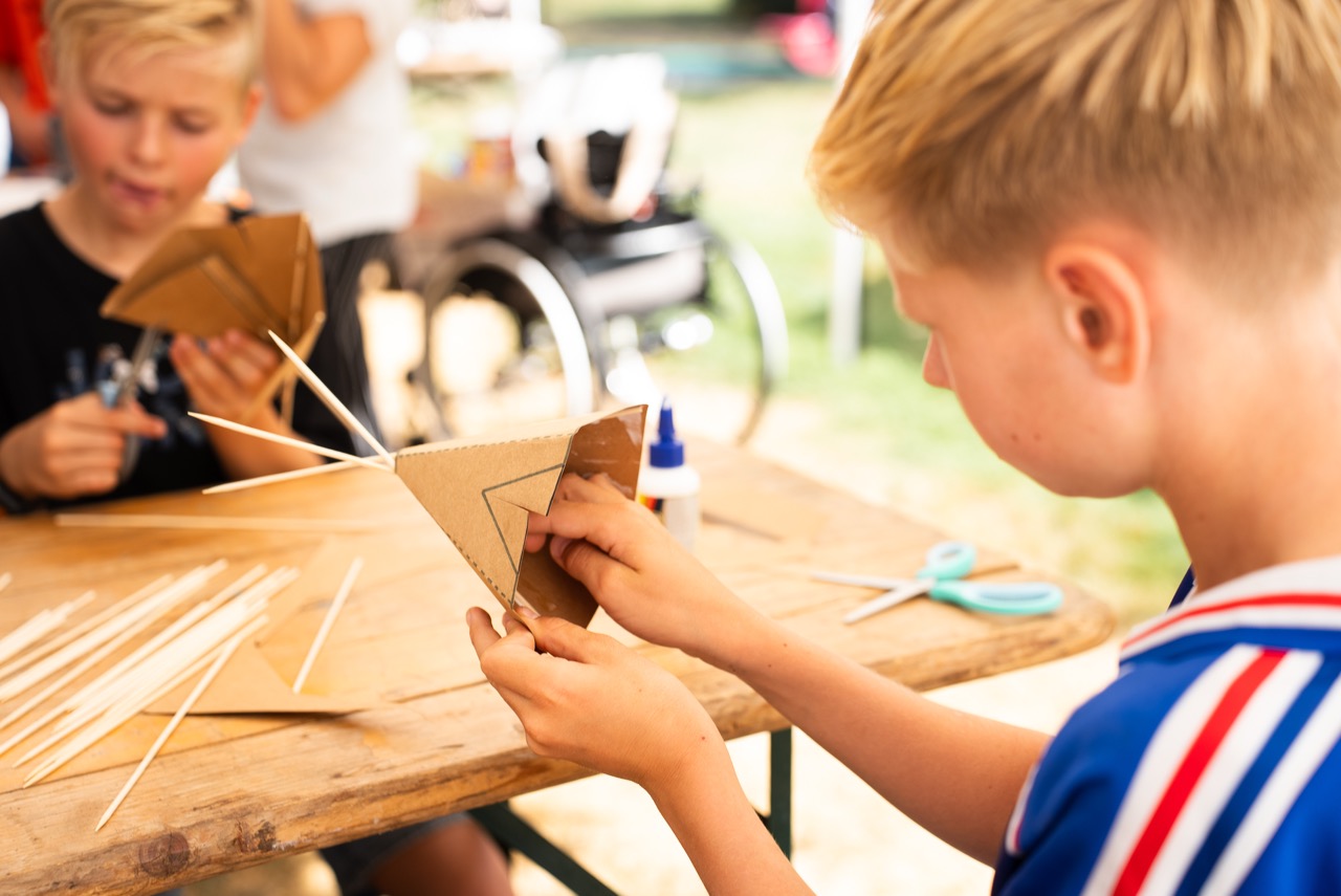 Twee jongens knutselen samen met karton aan de knutseltafel tijdens de Kidsdag van Mozaiek0548