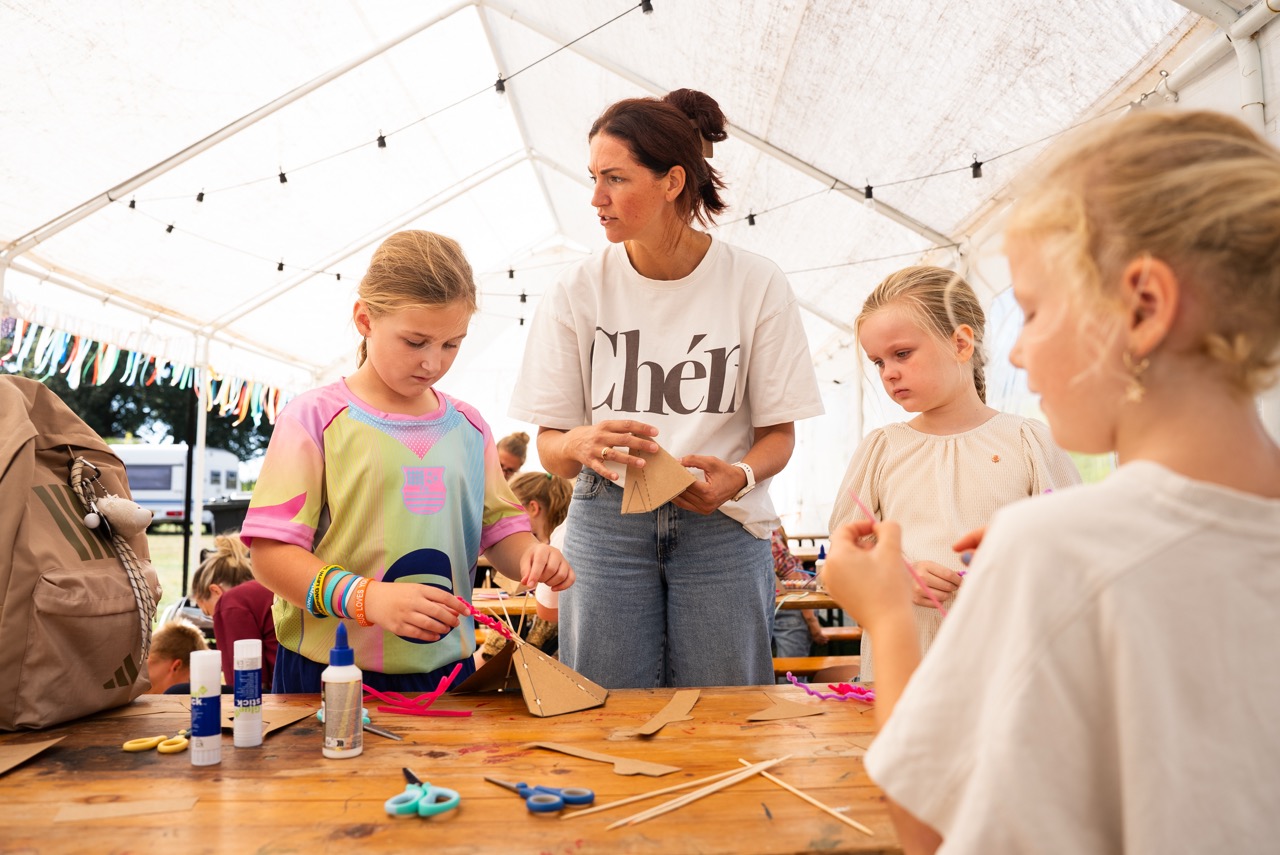 Kinderen en een begeleidster knutselen onder de witte tent met lichtjes tijdens de Kidsdag van Mozaiek0548