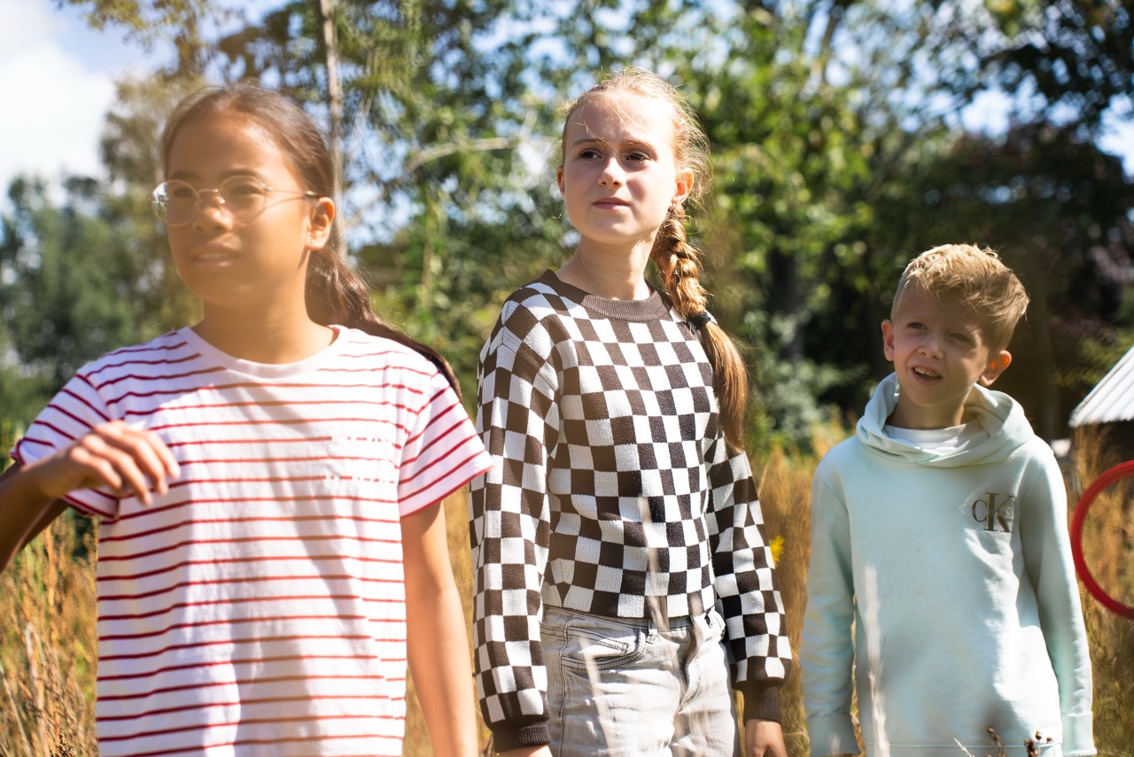 Drie meisjes staan samen buiten op het terrein tijdens de Kidsdag van Mozaiek0548