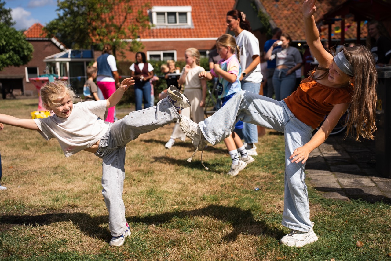 Kinderen rennen en spelen op het grasveld bij het gebouw tijdens de Kidsdag van Mozaiek0548