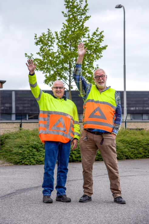 Twee verkeersregelaars in hesjes zwaaien op de parkeerplaats bij de kerk