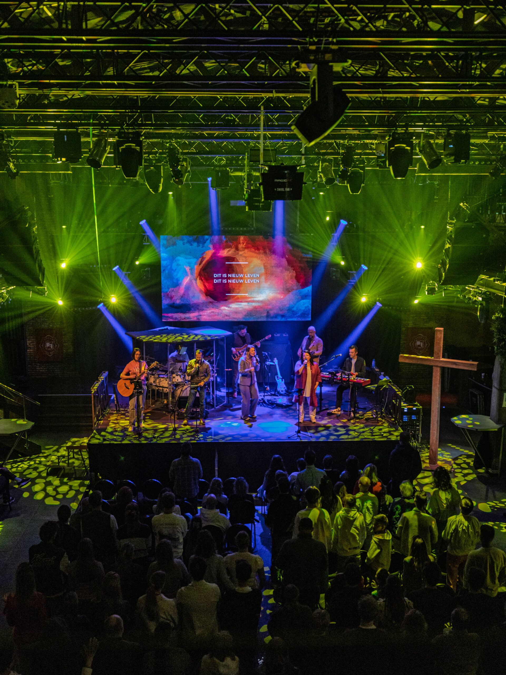 Worshipband speelt op het podium met groene lichtshow terwijl de zaal toekijkt