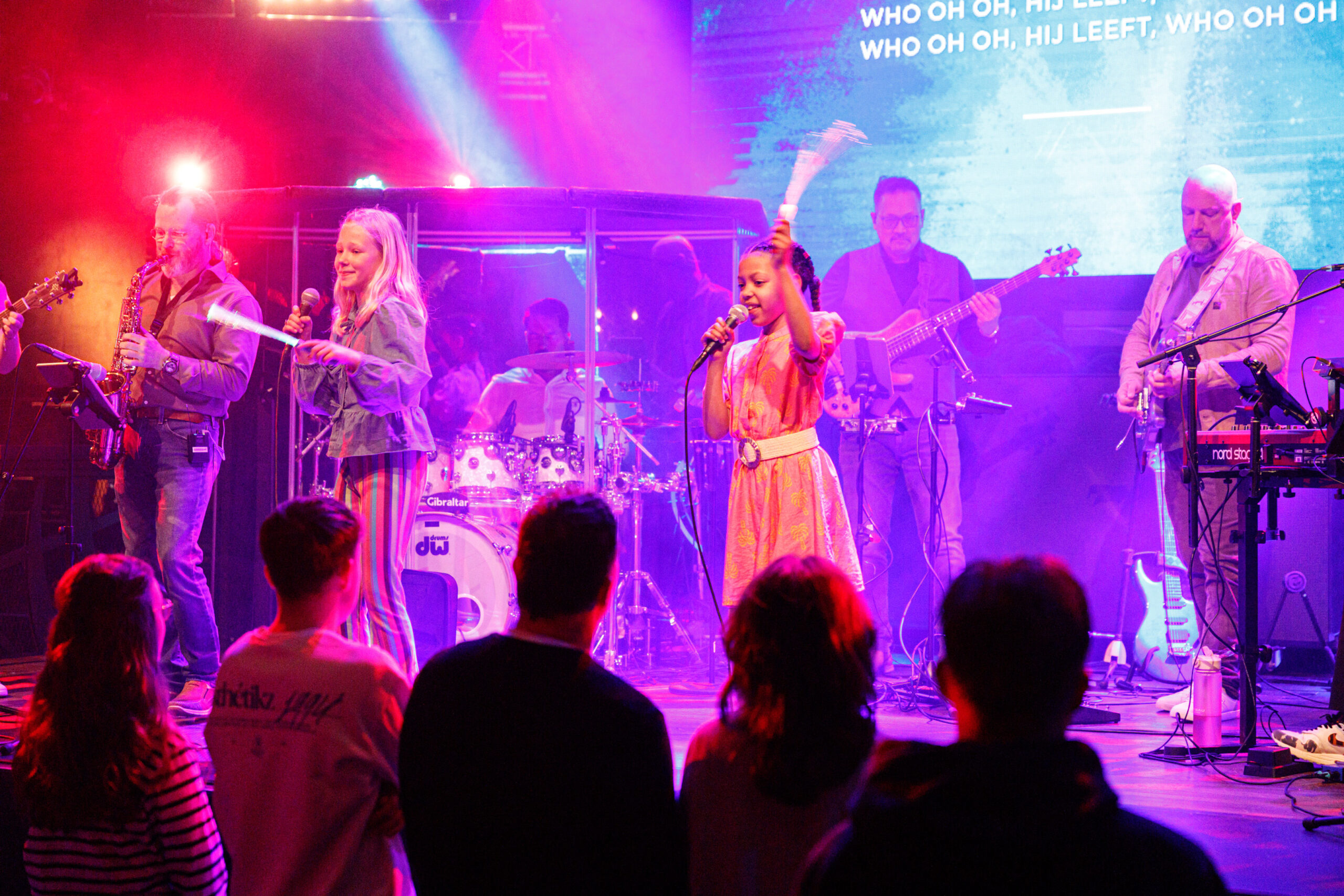 Twee zangeressen zingen in de microfoon terwijl de band achter hen speelt